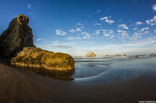 Bandon Beach on the Oregon Coast, with dramatic sea stacks rising from the ocean and waves along the sandy shoreline.
