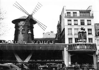 Vintage Can‑Can dancers at the Moulin Rouge in Paris, wearing layered skirts and stockings, captured mid‑kick on the cabaret stage.