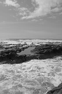 Rugged Cove Beach with rocky shoreline and towering Cape Perpetua above the Pacific Ocean.