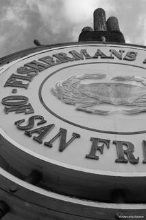 Famous Fisherman’s Wharf sign with colorful shops and visitors along the San Francisco waterfront.