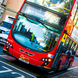 Classic red London double-decker bus traveling along a busy London street, a familiar symbol of the city’s public transportation