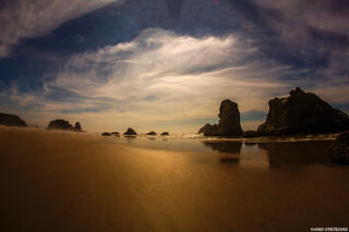 Scenic Bandon Beach on the Oregon Coast, featuring towering rock formations surrounded by ocean waves and a sandy shoreline.