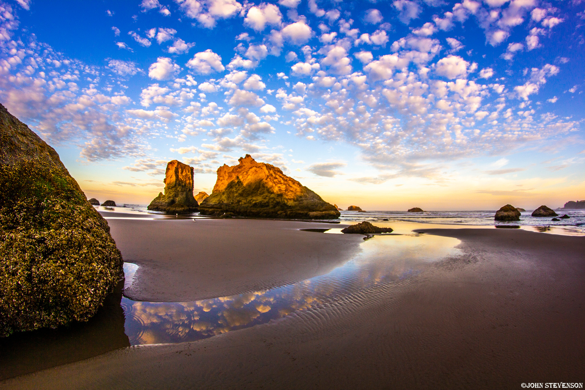 Dramatic sea stacks rise from the ocean at Bandon Beach along the Oregon Coast, with waves rolling onto the sandy shoreline